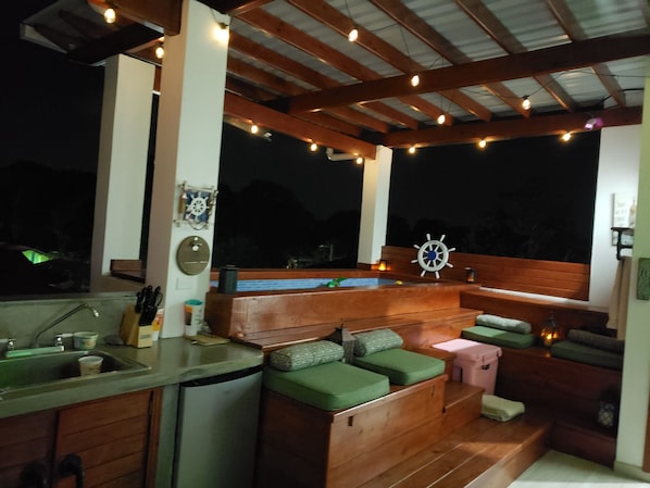 An outdoor kitchen area with a sink, countertop, and wooden seating.