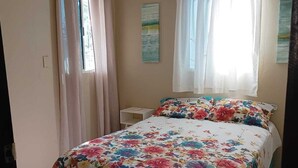 Une chambre à coucher avec un lit, des rideaux, une fenêtre et un climatiseur fixé au mur.