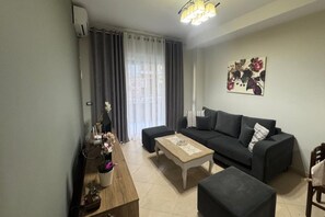 A living room with a sofa, a coffee table, a TV, and a painting on the wall. - Ionian Escape 002, Vlore, Albania (Vlore)