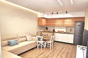 A modern kitchen with wooden cabinets, a dining area with a table and chairs, and a built-in refrigerator. - Ionian Escape 038, Vlore, Albania (Vlore)