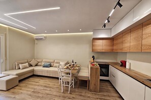 A modern kitchen with wooden cabinets, a dining area with a beige sofa, and a built-in oven. - Ionian Escape 038, Vlore, Albania (Vlore)
