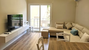 A modern living room with a flat-screen TV, a sofa, a dining table, and a balcony with a railing. - Ionian Escape 038, Vlore, Albania (Vlore)