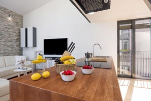 A modern living room with a wooden coffee table, a television, and a balcony with a view.