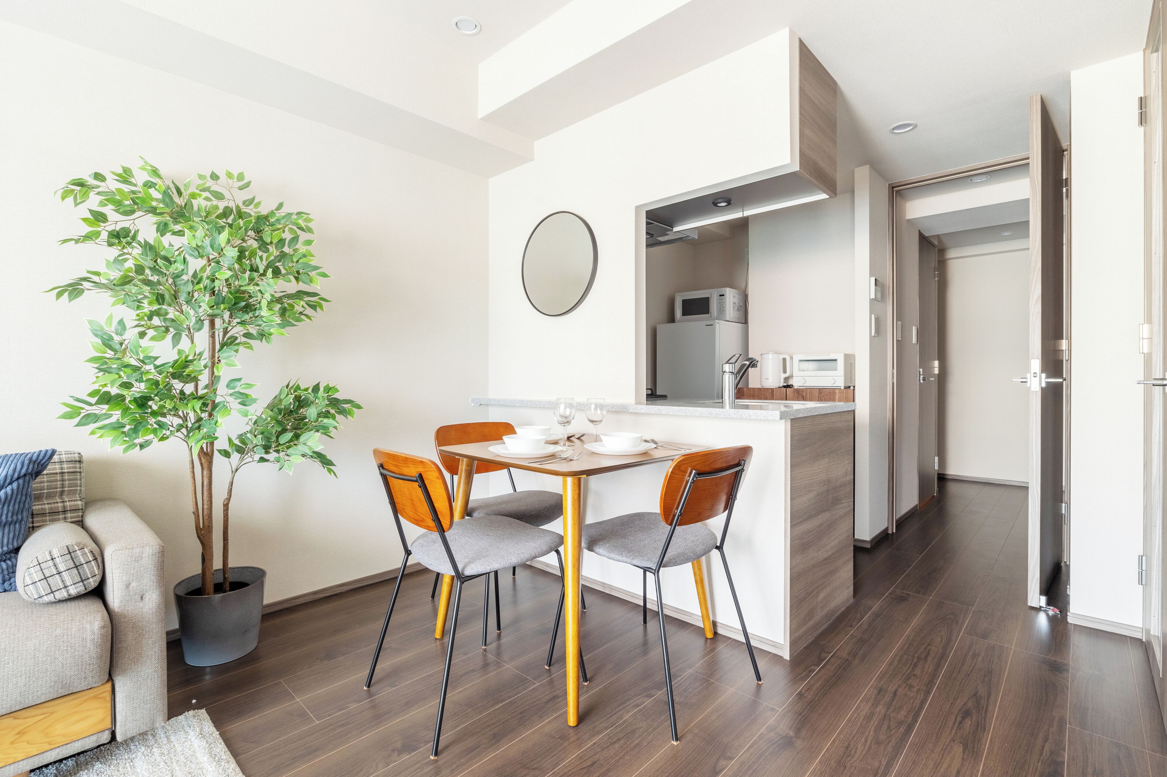 A modern kitchen with a dining table, chairs, a potted plant, and a microwave.
