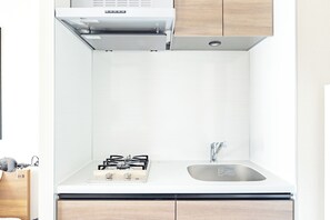 A kitchen with a gas stove, a sink, and wooden cabinets.