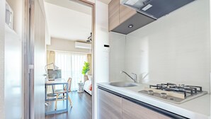 A modern kitchen with a built-in stove, a sink, and wooden cabinets. - Dash Living Osaki (Shinagawa-ku)