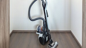 A compact room with a vacuum cleaner, a white shelf, and a hanging towel. - Dash Living Osaki (Shinagawa-ku)