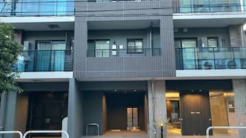 Un edificio de varios pisos con un diseño arquitectónico moderno, que incluye balcones, ventanas amplias y una entrada protegida por una reja.