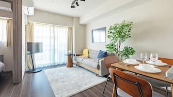 A modern living room with a sofa, dining table, and a potted plant.