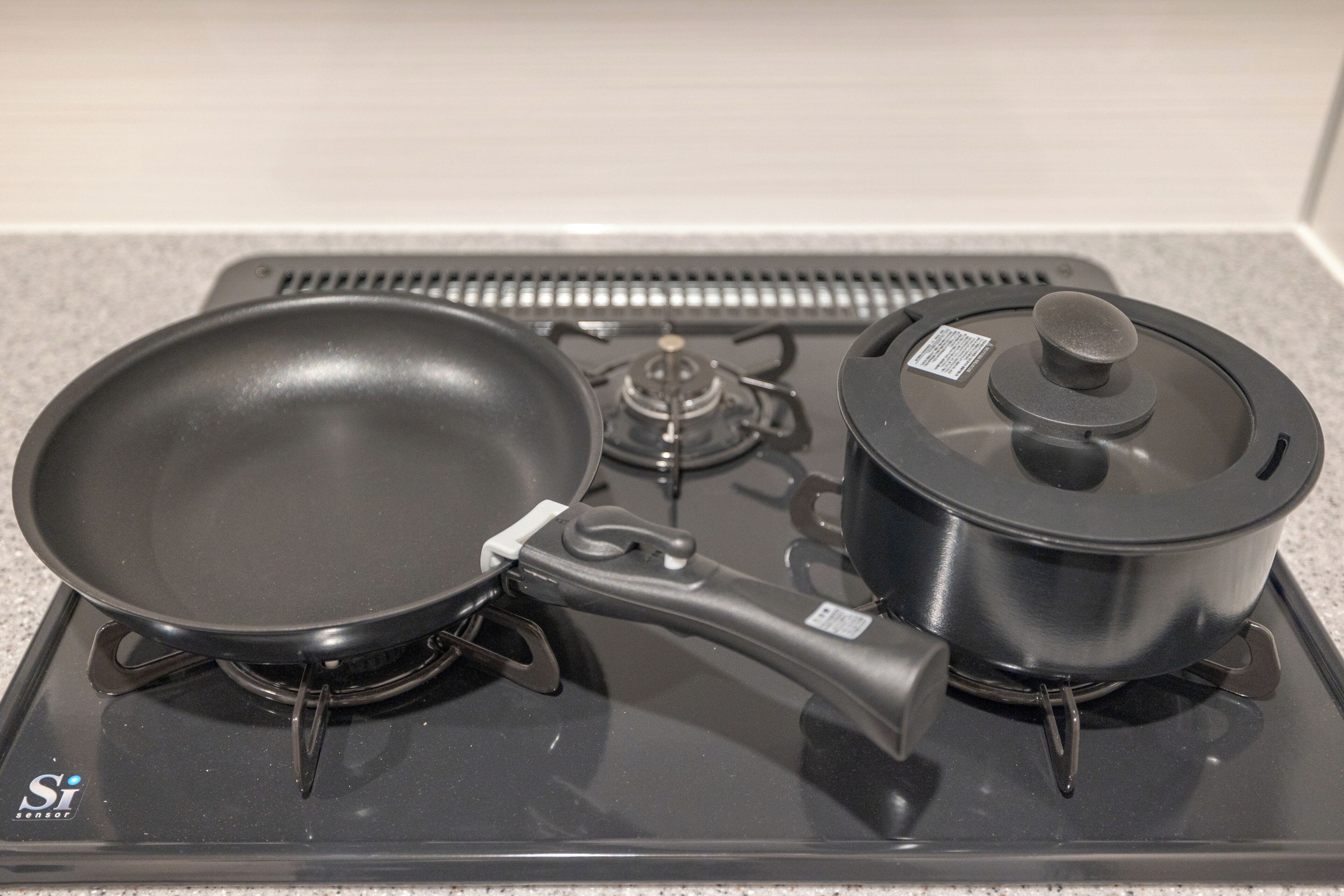 A stove with a frying pan and a pot on a portable gas stove.