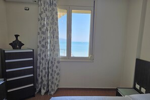 A room with a bed, a dresser, a window with a view of the sea, and a curtain with a floral pattern. - Casa Sul Mare, Vlore, Albania (Vlore)