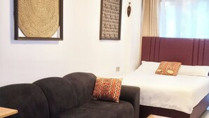 Habitació amb sofà, llit, taula de cafè, planta en test i obra d'art a les parets.