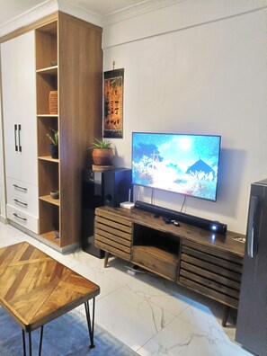 A living room with a TV, wooden cabinet, and a coffee table. - Prime Kilimani Location,5 mins Walk to Yaya Centre, Mersen Studio (Nairobi)