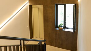 A modern staircase with a handrail, a small window with a plant, and a door leading to another room. - Velaris Partial Sea View Balcony 102, Vlore, Albania (Vlore)