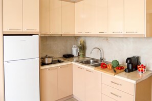 Eine Küche mit Kühlschrank, Herd, Spüle und verschiedenen Küchenutensilien.