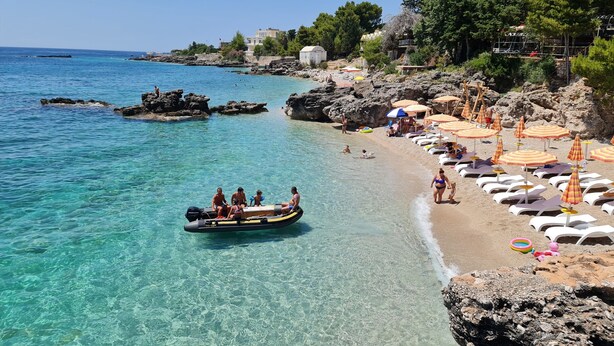 A beach with clear water, a rocky shoreline, and umbrellas. - Velaris Partial Sea View Balcony 102, Vlore, Albania (Vlore)