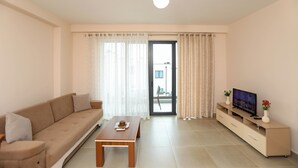 A living room with a sofa, coffee table, TV stand, and curtains. - Velaris Partial Sea View Balcony 102, Vlore, Albania (Vlore)