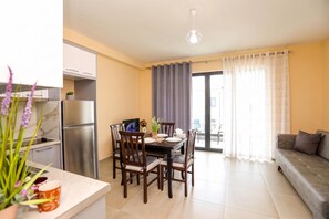 A modern kitchen with a built-in oven and a dining area with a table and chairs. - Velaris Partial Sea View Balcony 101, Vlore, Albania (Vlore)