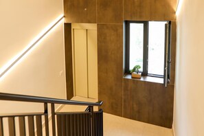 A modern staircase with a handrail, a window with a plant, and a wall with a recessed panel. - Velaris Partial Sea View Balcony 101, Vlore, Albania (Vlore)