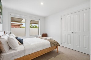 Un dormitorio con cama, mesita de noche, armario y ventana con vistas al exterior.