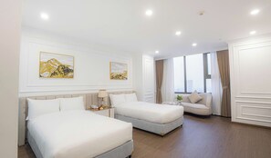 Habitación de hotel con dos camas, un sofá, un ventanal con vistas a la ciudad y dos cuadros colgados en la pared.