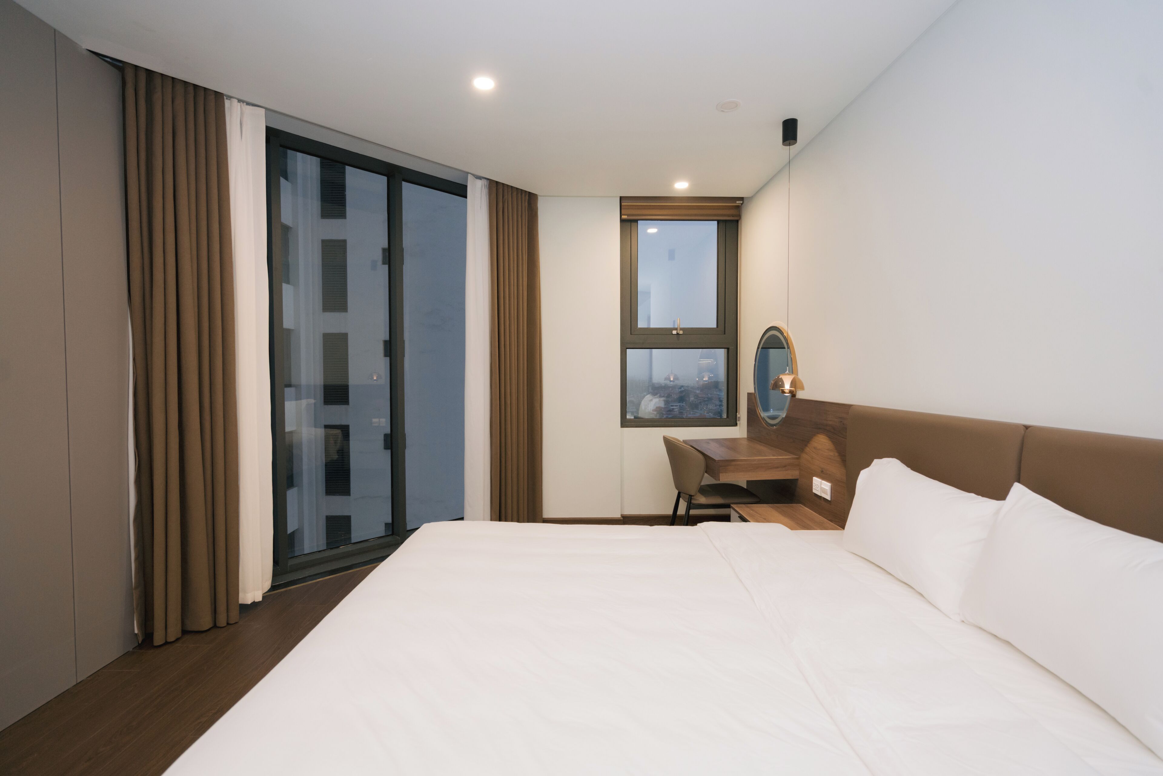 Une chambre d’hôtel avec un grand lit, un bureau, une chaise, une fenêtre donnant sur un beau paysage et une porte coulissante.