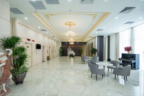 A spacious lobby with a marble floor, a grand chandelier, a piano, and modern seating. - Prime Hotel Thai Nguyen (Phan Dinh Phung)