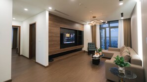 Uma sala de estar moderna com televisão de tela plana, um sofá, uma mesa de centro e um vaso com planta.
