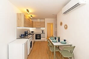 A compact kitchen with a washing machine, a microwave, and a coffee maker. - GuestReady - Modern flat 5 minutes from the beach (Valencia)