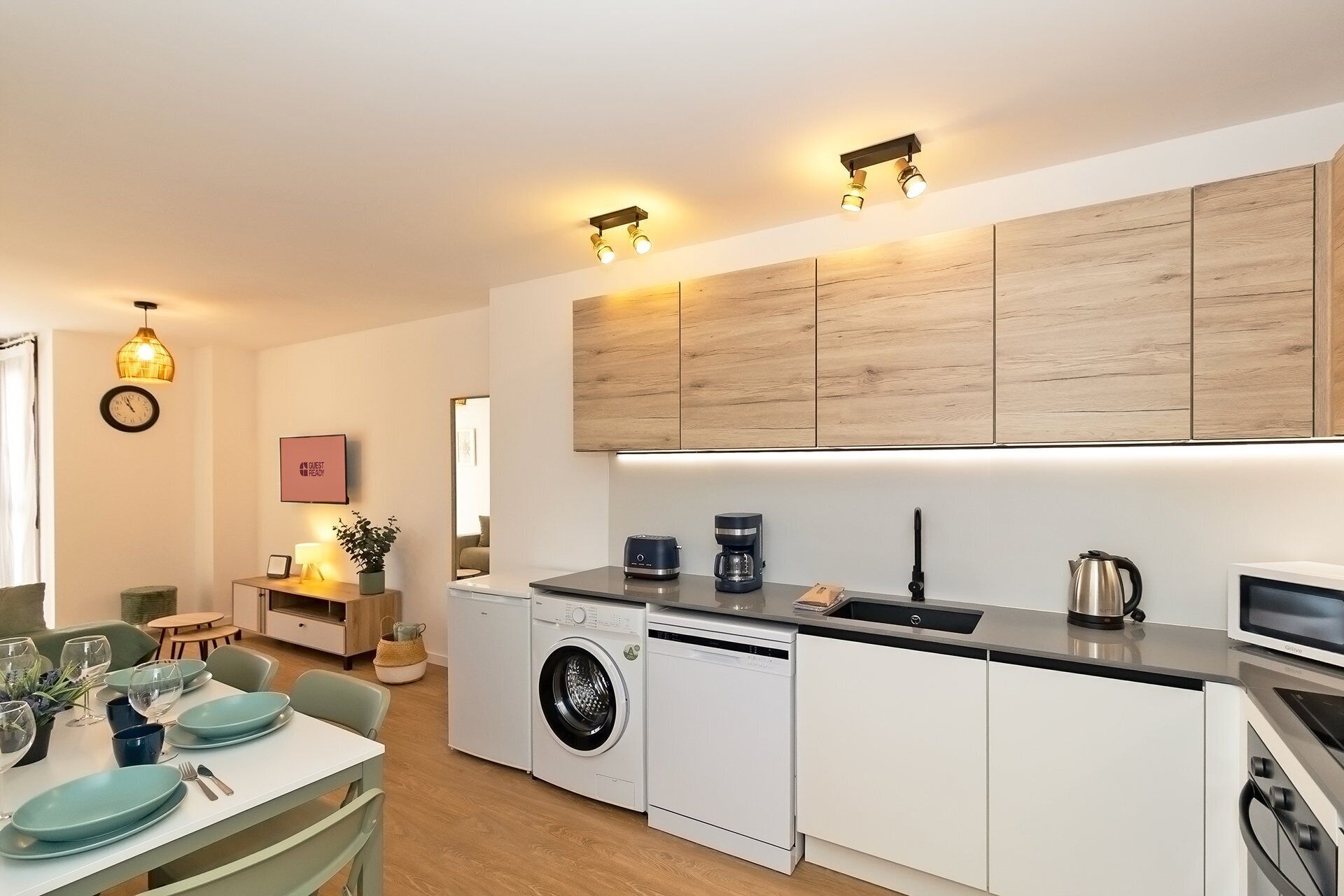 Een moderne keuken met een inbouw wasmachine, een koffiezetapparaat en een waterkoker op het aanrecht.
