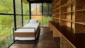 Een moderne slaapkamer met een bed, een plafondventilator en grote ramen.