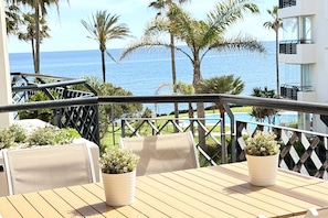 A balcony with a view of the sea, wooden furniture, and potted plants. - MI CAPRICHO BEACHFRONT: 210 with sea view (Mijas)
