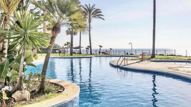 A swimming pool surrounded by palm trees and a view of the sea. - MI CAPRICHO BEACHFRONT: 210 with sea view (Mijas)