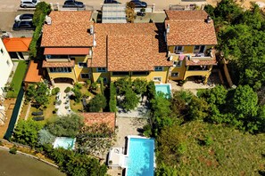 A multi-story building with a tiled roof, a swimming pool, and surrounding greenery. - Pool and Garden Apartment Hortenzija 3, Kostrena, Croatia (Kostrena)