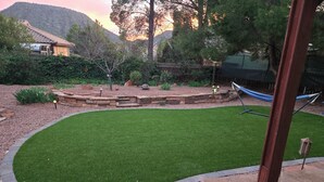 A landscaped backyard with a curved lawn, stone retaining wall, and a hammock. - Spacious, zen, fully-equipped 3 bed/2 bath home with red rock views (Sedona)