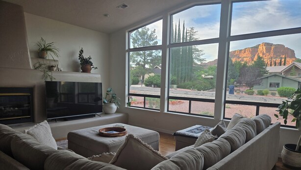 A living room with a large window, a flat-screen TV, a fireplace, and a sofa. - Spacious, zen, fully-equipped 3 bed/2 bath home with red rock views (Sedona)