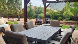 An outdoor patio with a wooden pergola, a dining table with chairs, and a patterned rug. - Spacious, zen, fully-equipped 3 bed/2 bath home with red rock views (Sedona)