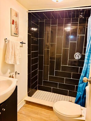 A bathroom with a shower, a toilet, and a sink.