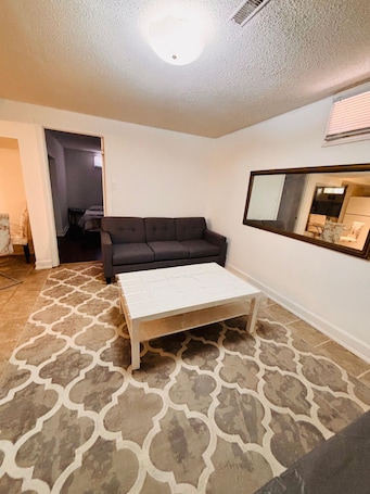 A living room with a sofa, a coffee table, and a patterned rug.. Welcome! This is a private 1-bedroom lower-level basement suite in our home.