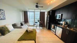 Et hotelværelse med seng, sofa, spisebord og tekøkken.