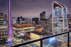 Eine Skyline mit beleuchteten Wolkenkratzern, darunter ein markantes Gebäude mit der Beschriftung 'PWC'.