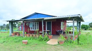 Uma casa de tijolos vermelhos com telhado azul e varanda coberta.