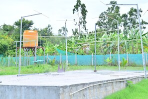 A concrete platform with a metal structure, a water tank, and a green netted fence with vegetation.
