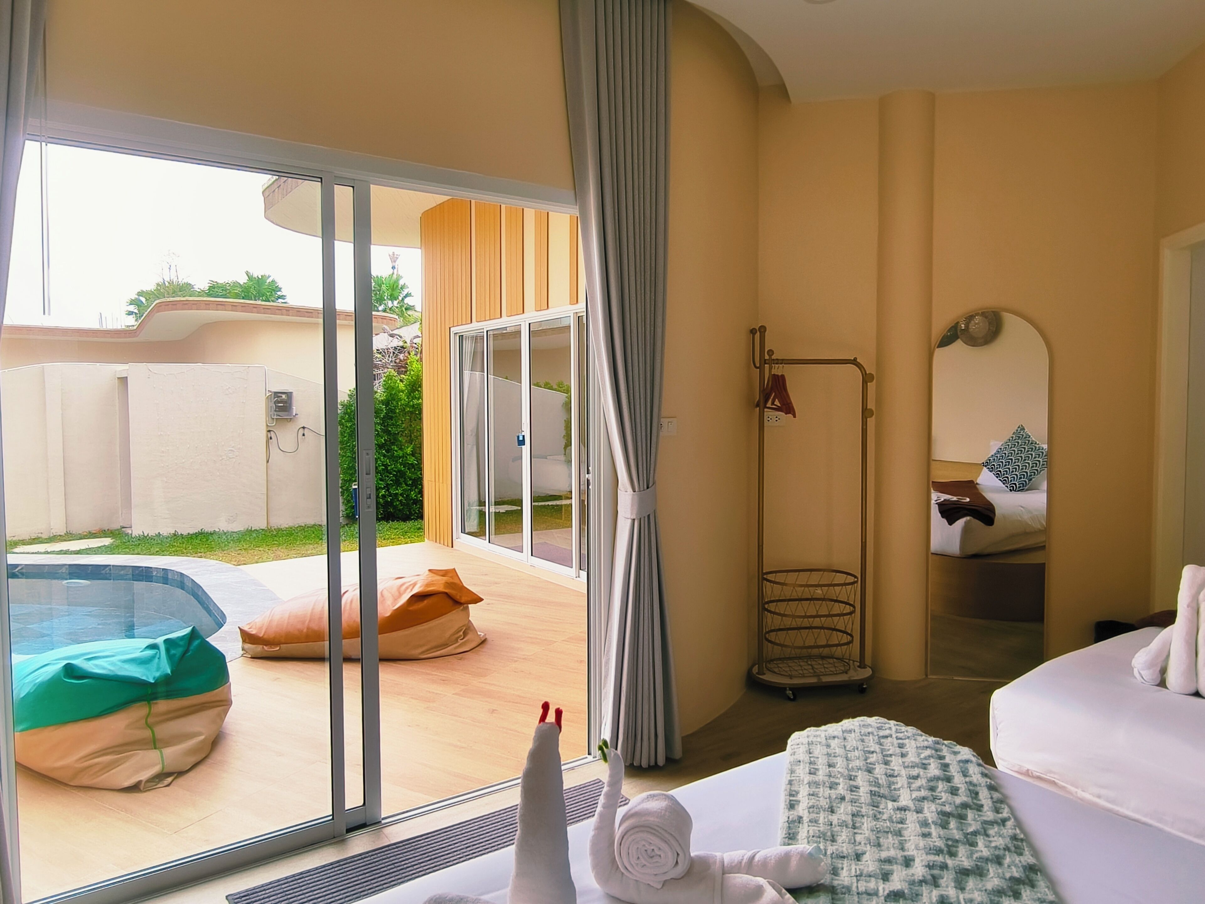 Et hotelværelse med skydedør til en pool, en seng, et natbord og et spejl.