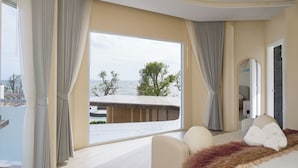 Un dormitorio con un ventanal grande, una cama y vista al mar.