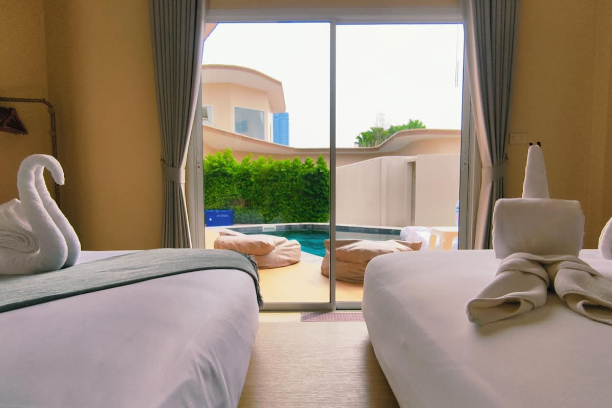 A hotel room with two beds, a view of a swimming pool, and a balcony.