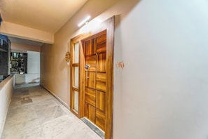A hallway with a wooden door, a tiled floor, and a wall-mounted sign.