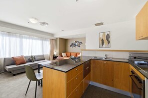 Eine moderne Küche mit Holzschränken, einer zentralen Kochinsel und einem Essbereich mit einer Couch und Stühlen.