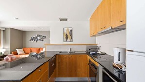 Eine moderne Küche mit Holzschränken, einer schwarzen Arbeitsplatte und einem eingebauten Backofen.