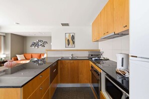 Eine moderne Küche mit Holzschränken, einer schwarzen Arbeitsplatte und einem eingebauten Backofen.
